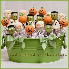 a green bucket filled with halloween candies and pumpkins on top of each other