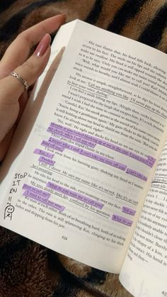 a person holding an open book with writing on the pages in purple and black ink