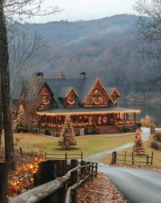 a log cabin with christmas lights on the front and side of it is surrounded by trees