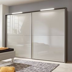 a bedroom with a bed, rug and sliding glass closet doors in the middle of it