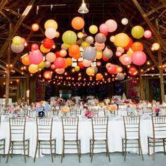 a large room with tables and chairs covered in paper lanterns hanging from the rafters