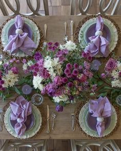 the table is set with purple and white flowers, silverware, and napkins