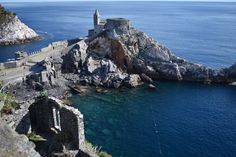 an old castle perched on top of a rocky cliff next to the ocean with clear blue water