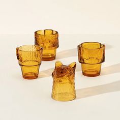 four yellow glass cups sitting next to each other