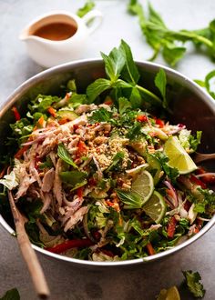 a salad in a bowl with limes, peppers and other vegetables on the side