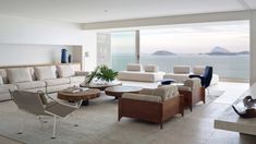 a living room filled with furniture next to a large glass window overlooking the ocean and mountains