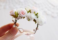 a hand holding a flower headband with white and pink flowers