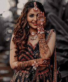 a woman with her hands painted in hendi and jewelry, posing for the camera