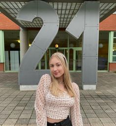 blonde girl standing in front of huge number 21 because it’s her 21st birthday, wearing white polka dot shitt, silver crown, vivienne westwood necklace and having silver gemstone makeup Birthday Makeup Looks