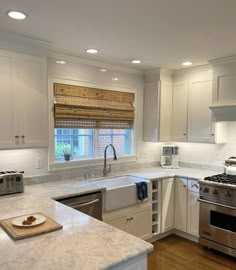 a kitchen with white cabinets and marble counter tops, stainless steel appliances and an oven