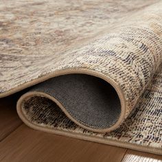 an area rug is laying on the floor next to a wood flooring board with a beige and blue pattern