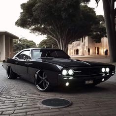 a black car parked on the side of a road next to a tree and building