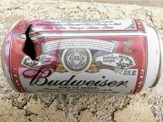 an empty budweiser beer can sitting on the ground