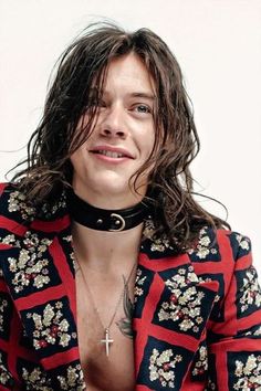 a man with long hair and piercings on his chest is posing for the camera