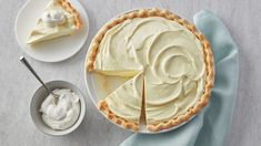 a white plate topped with a pie next to a bowl of whipped cream