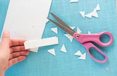 someone is cutting out paper with scissors on a blue tablecloth that has white arrows