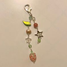 a key chain with charms attached to it on a white surface, including an apple and star