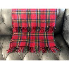 a red plaid blanket sitting on top of a gray leather couch next to a pillow