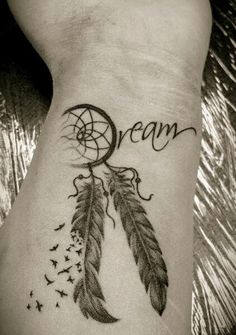 a woman's wrist with a dream catcher tattoo on it and the words dream written in cursive writing