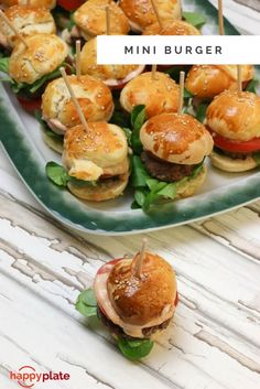 mini burgers with toothpicks in them on a platter next to other small sandwiches