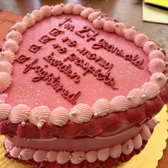 a birthday cake with pink frosting and writing on the top is sitting on a yellow plate