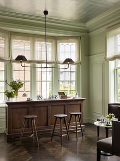 a kitchen with two bar stools next to a table and chairs in front of windows