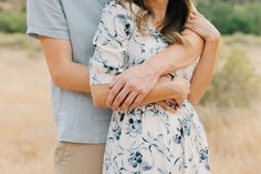 a man and woman embracing each other in an open field