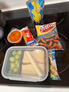 the meal is prepared and ready to be eaten on the stove top, including fruit, crackers, candy bars, and other snacks