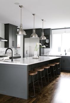 a kitchen with an island and bar stools next to the counter top, along with several lights hanging from the ceiling