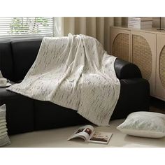 a living room with a black couch and white throw blanket on top of the sofa