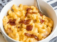 a white bowl filled with macaroni and cheese on top of a striped napkin