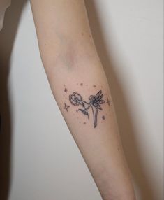 a woman's arm with a tattoo on it that has flowers and stars around it