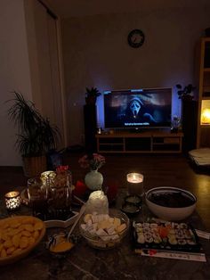 a table topped with food and candles next to a tv screen in a living room