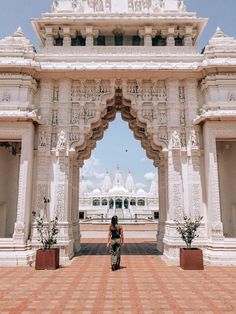 a woman standing in front of a white building with arches and pillars on the sides