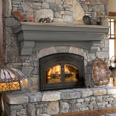 a stone fireplace in a living room with two lamps on either side of the fire place