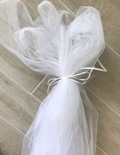 a white tulle bag on the floor with some string tied to it's side