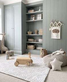 a baby's room with grey walls and white rugs, wooden toy giraffe on the floor