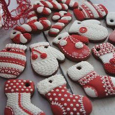 decorated cookies are arranged in rows on a table with white and red decorations around them