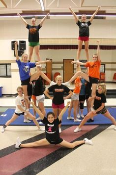 a group of young women standing on top of each other in front of a gym floor