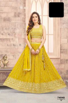 Like a sunbeam, she radiated in her sunshine yellow lehenga, the delicate gold zari embroidered buttas sparkling like rays of light on a cloudless day. The broad embroidered border seemed to shine with warmth, as if the very essence of happiness had been woven into the fabric. The zari embroidered sleeveless blouse added a touch of vibrancy, like the first bloom of summer. The simple tonal dupatta with embroidered border fluttered behind her like a gentle breeze on a sunny afternoon. Her beauty Yellow Dresses With Gold Embroidery For Festivals, Yellow Dress With Gold Embroidery For Festivals, Yellow Lehenga With Mirror Work For Navratri, Navratri Yellow Lehenga With Mirror Work, Yellow Bollywood Lehenga With Mirror Work, Bollywood Style Yellow Lehenga With Mirror Work, Yellow Mirror Work Lehenga For Festivals, Yellow Lehenga With Mirror Work For Eid, Yellow Mirror Work Choli For Eid