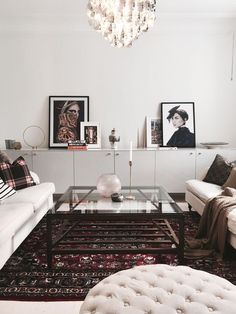 a living room filled with white furniture and pictures on the wall above it's coffee table