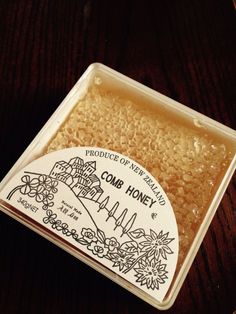 a container filled with honey sitting on top of a wooden table