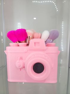 a pink camera with makeup brushes in it