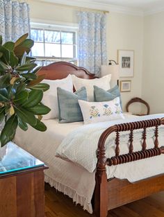 a bed sitting in a bedroom next to a window with blue and white drapes