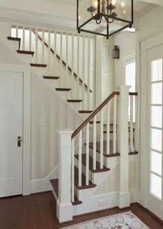 a chandelier hanging from the ceiling in front of a staircase leading to a second floor