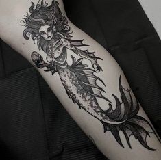 a woman's leg with a black and white tattoo design on her left arm