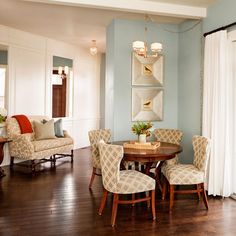 a dining room with blue walls and wood flooring is pictured in this image, there are four chairs around the table