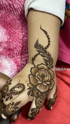 a woman's hand with henna tattoos on it and flowers painted on the wrist