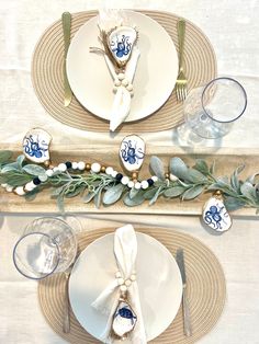 the table is set with plates, silverware and greenery for an elegant touch