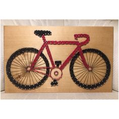 a red bicycle with black and white beads is mounted on a wooden plaque that says bike